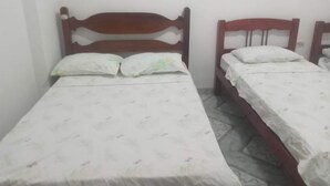 A small, single-bed room with a wooden headboard and a plain bedspread.