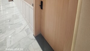 A hallway with a marble floor, a wooden door with the number 42, and a white wall with a light fixture. - Charming Apartment 42 (Casablanca)