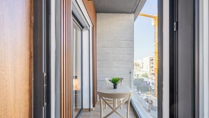 A narrow balcony with a table and chairs, a potted plant, and a view of a construction site. - Charming Apartment 42 (Casablanca)