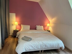 Cozy attic-style room with a large bed, bedside tables, and a sloped ceiling.
