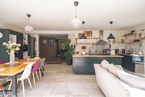 Une cuisine moderne avec un îlot central, un coin repas avec des chaises et un canapé.