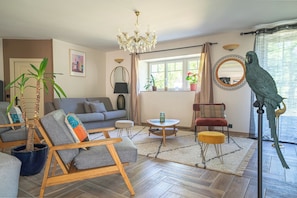 Un salon comprenant un canapé, un fauteuil, une table basse et un perroquet.