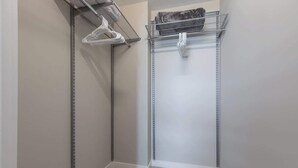 Ein begehbarer Kleiderschrank mit Metallregalen und Kleiderstangen.