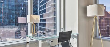 A modern office space with a glass desk, a black office chair, and a floor lamp.