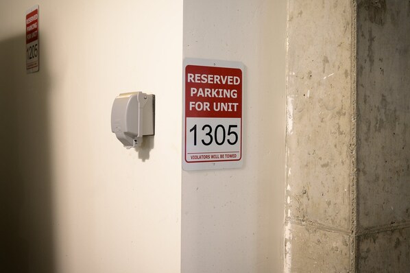 Señal en la pared que indica estacionamiento reservado para la unidad 1305, con advertencia de que los infractores serán remolcados.