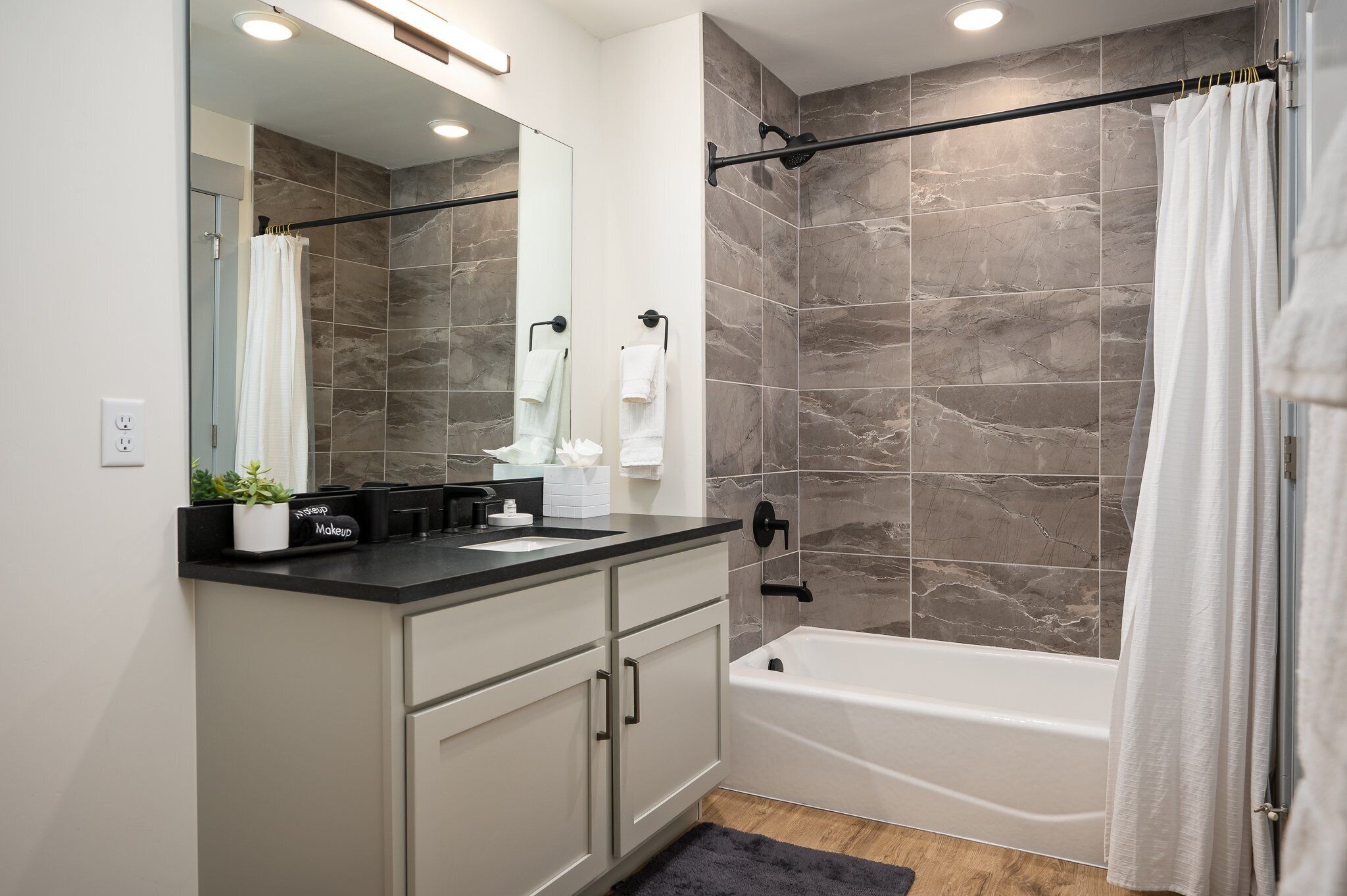 Un baño moderno con ducha, bañera, tocador con espejo y lavamanos.