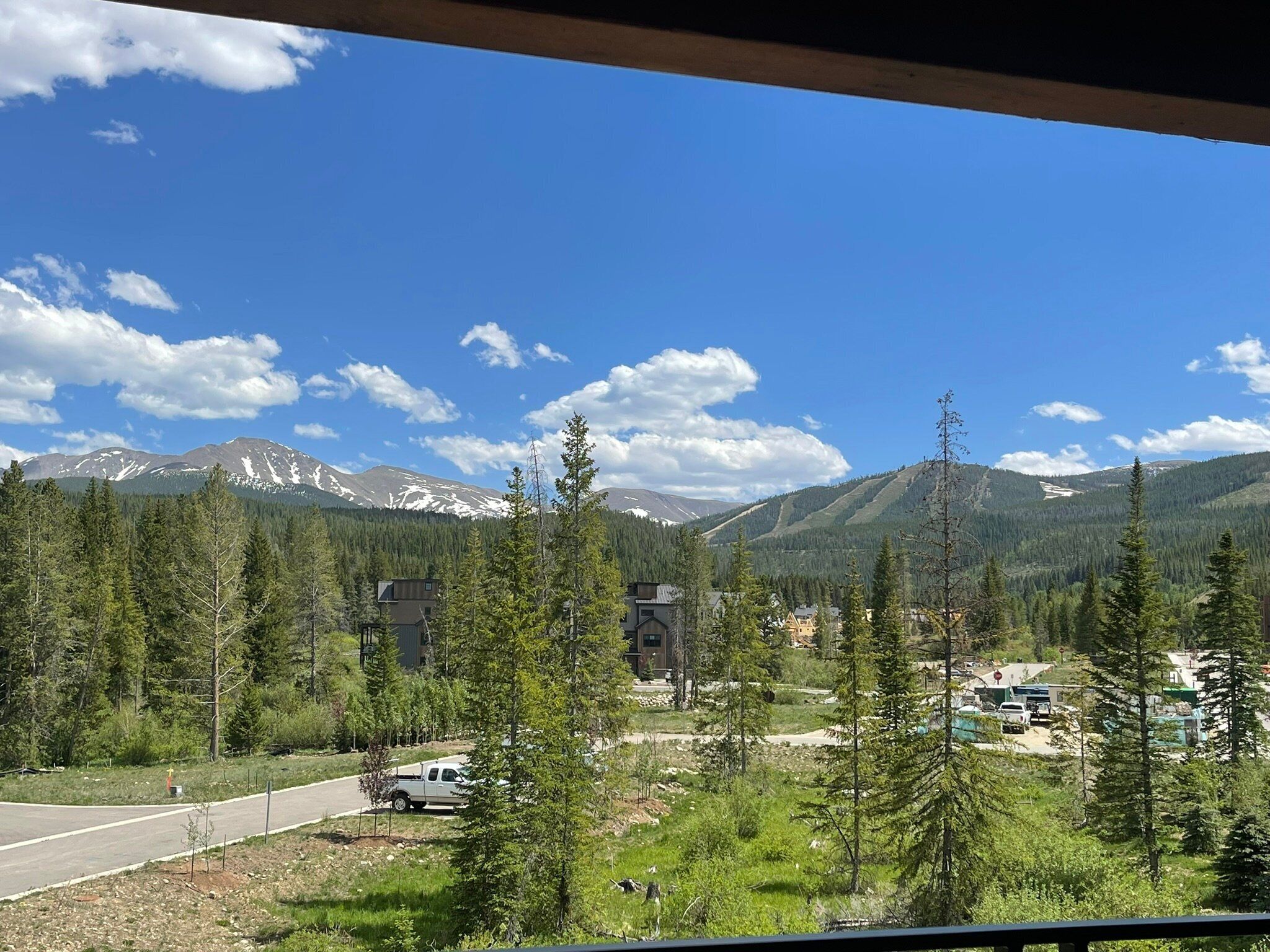 A mountain landscape with a road, buildings, and trees.