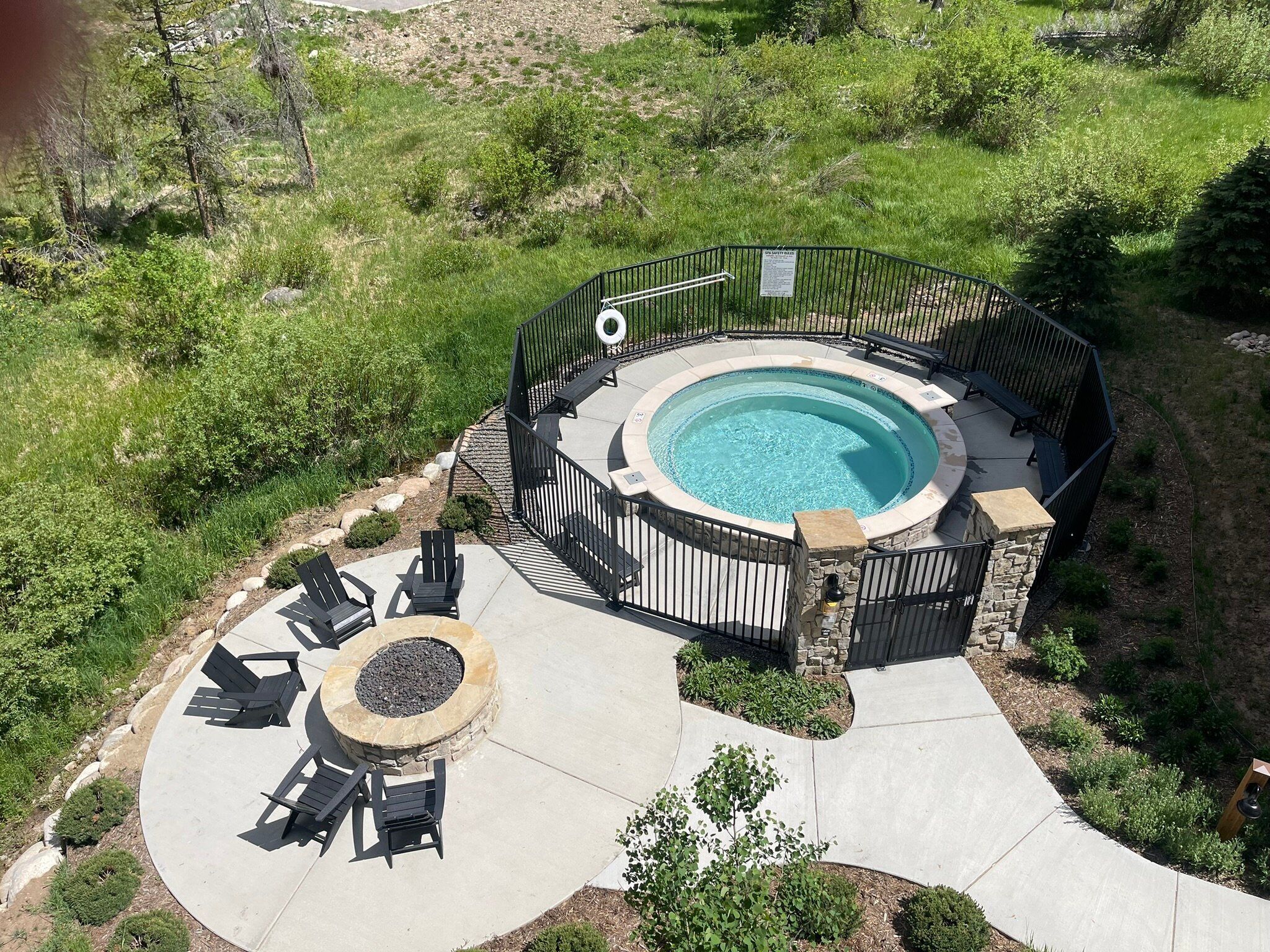 A circular hot tub surrounded by a stone deck and a pool.