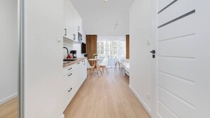 Eine moderne Küche mit weißen Schränken, ein Essbereich mit Tisch und Stühlen sowie ein Blick durch ein Fenster.