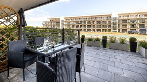 Eine Terrasse im Freien mit Tisch und Stühlen, ein Schwimmbad und ein Gebäude im Hintergrund.