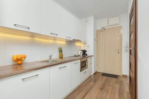 Eine moderne Küche mit weißen Schränken, einer Holzarbeitsplatte und einem Edelstahl-Spülbecken.