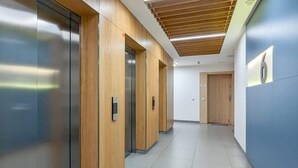A modern hallway with wooden paneling and elevators.