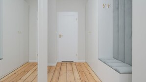 A hallway with wooden flooring, white walls, and a white door at the end.