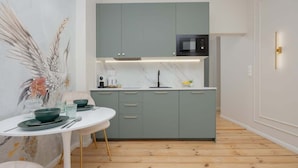 A modern kitchen with grey cabinets, a white countertop, and a black microwave.