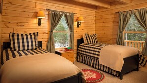Un dormitorio estilo cabaña con dos camas, paredes de madera y ventanas con cortinas.