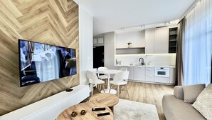 Ένα σύγχρονο σαλόνι με τηλεόραση επίπεδης οθόνης, ξύλινο τραπεζάκι σαλονιού και έναν καναπέ.