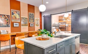 A modern kitchen with a central island, bar stools, and a large window.