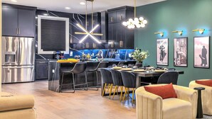Une cuisine moderne avec des meubles de couleur sombre, un réfrigérateur en acier inoxydable et un îlot central doté de tabourets de bar.