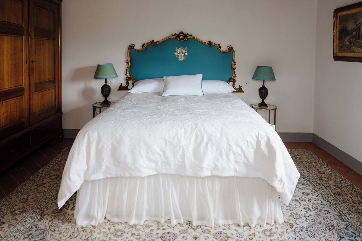 A bed with a white bedspread and a blue headboard, flanked by two bedside tables with lamps.