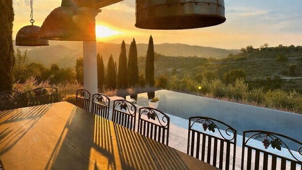 Une terrasse offrant une vue sur le coucher de soleil, une table avec des chaises et une rambarde.