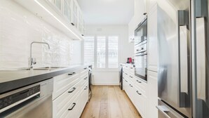 A modern kitchen with white cabinetry, stainless steel appliances, and a wooden floor.