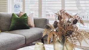 A living room with a grey sofa, a white coffee table, and a decorative vase with dried plants.