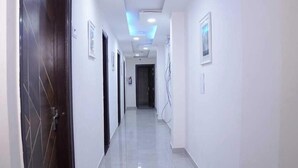 A long, narrow hallway with a tiled floor and a ceiling with recessed lighting. - Hotel Amazing House (New Delhi)