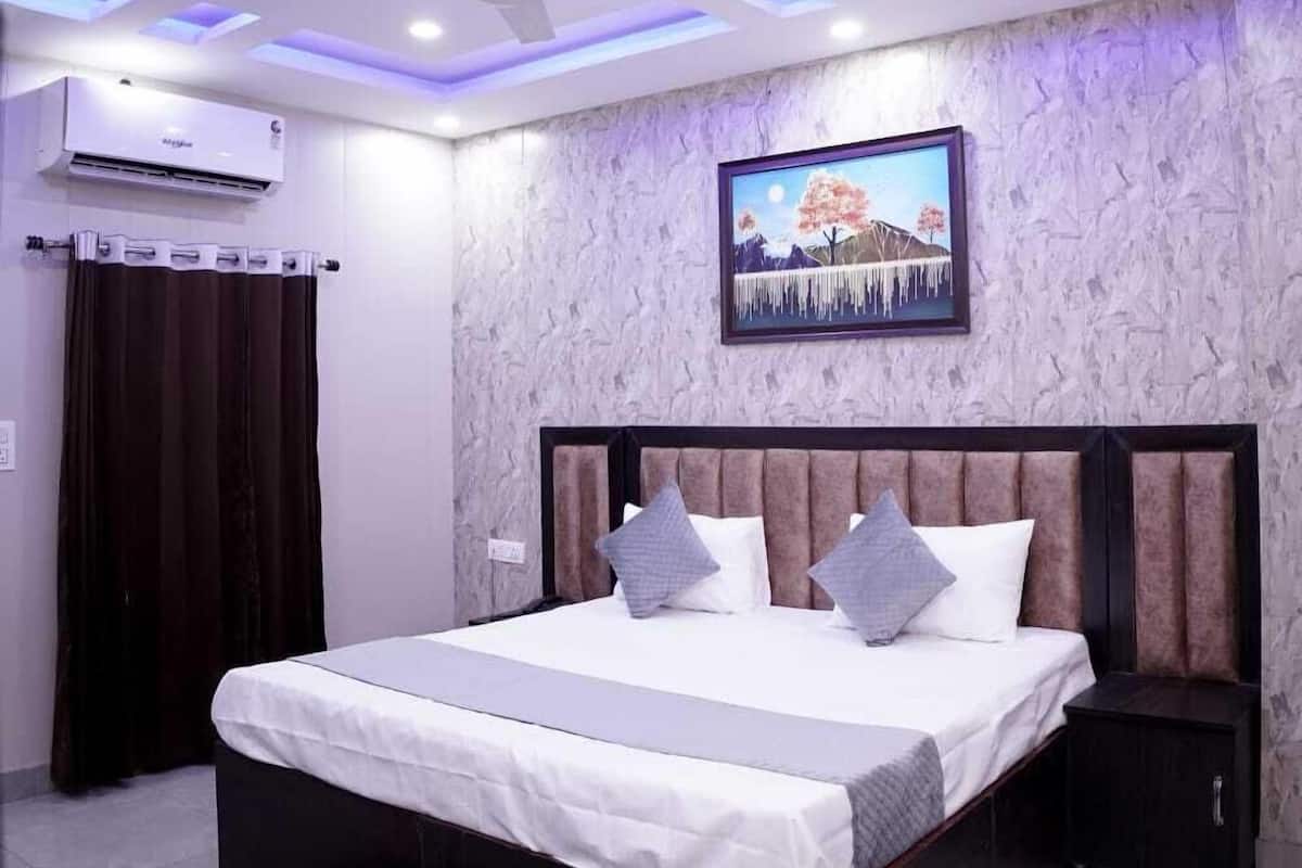 A modern bedroom with a large bed, ceiling fan, air conditioning unit, and a wall-mounted TV.