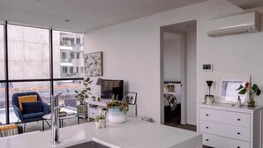 A modern living room with a large window, a flat-screen TV, a white dresser, and a dining area. - Bright & Stylish Terrace Retreat Richmond (Richmond)