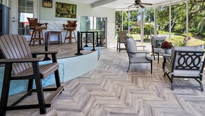 Une pièce spacieuse dotée d’un parquet en point de Hongrie, de grandes fenêtres offrant une vue sur l’extérieur, ainsi que de plusieurs coins salon avec des fauteuils et une table.