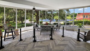 Une pièce spacieuse avec de grandes fenêtres, un parquet en point de Hongrie et une vue sur un lac et une maison rouge.