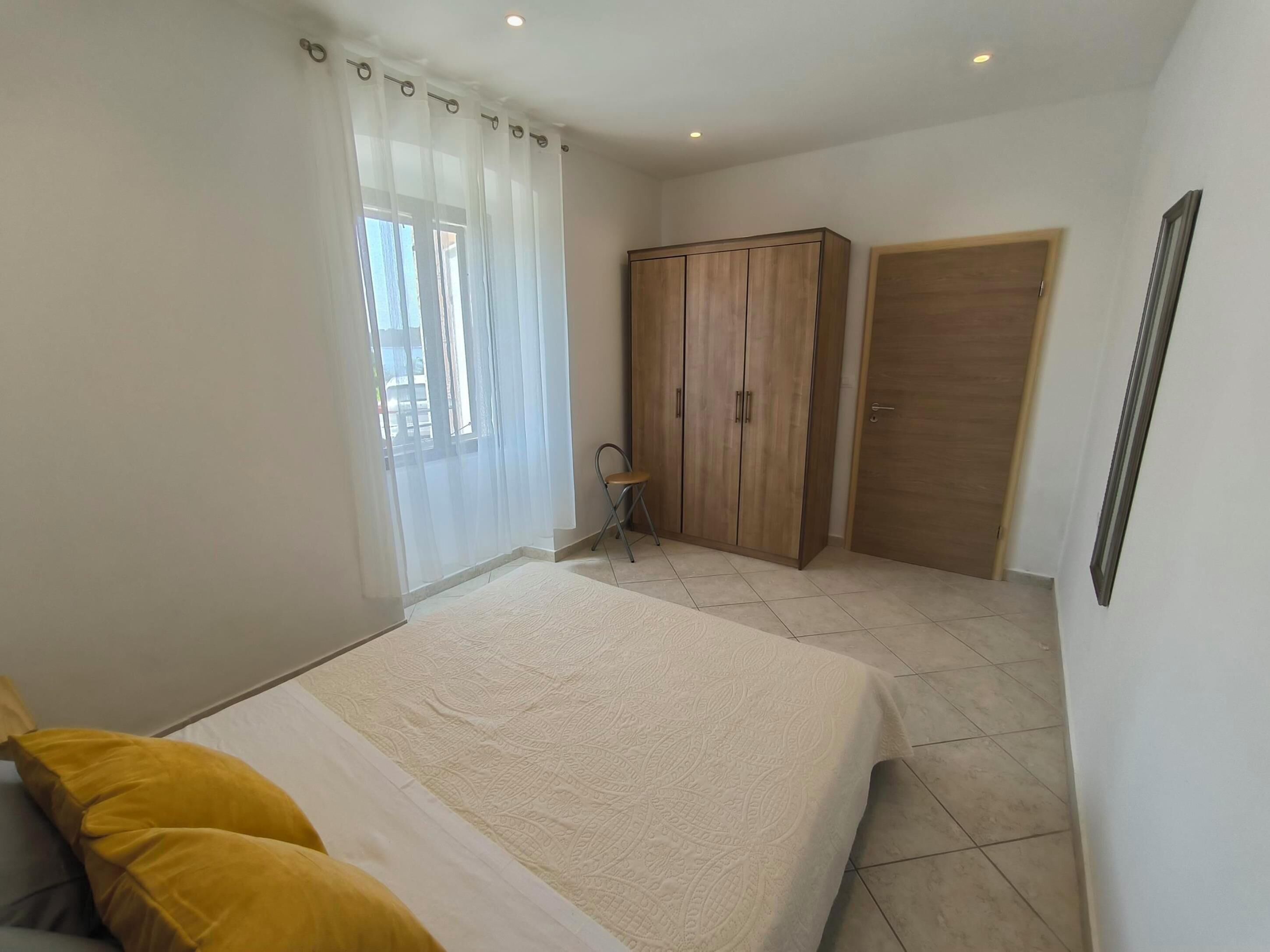 A bedroom with a bed, a wardrobe, a chair, and a door.