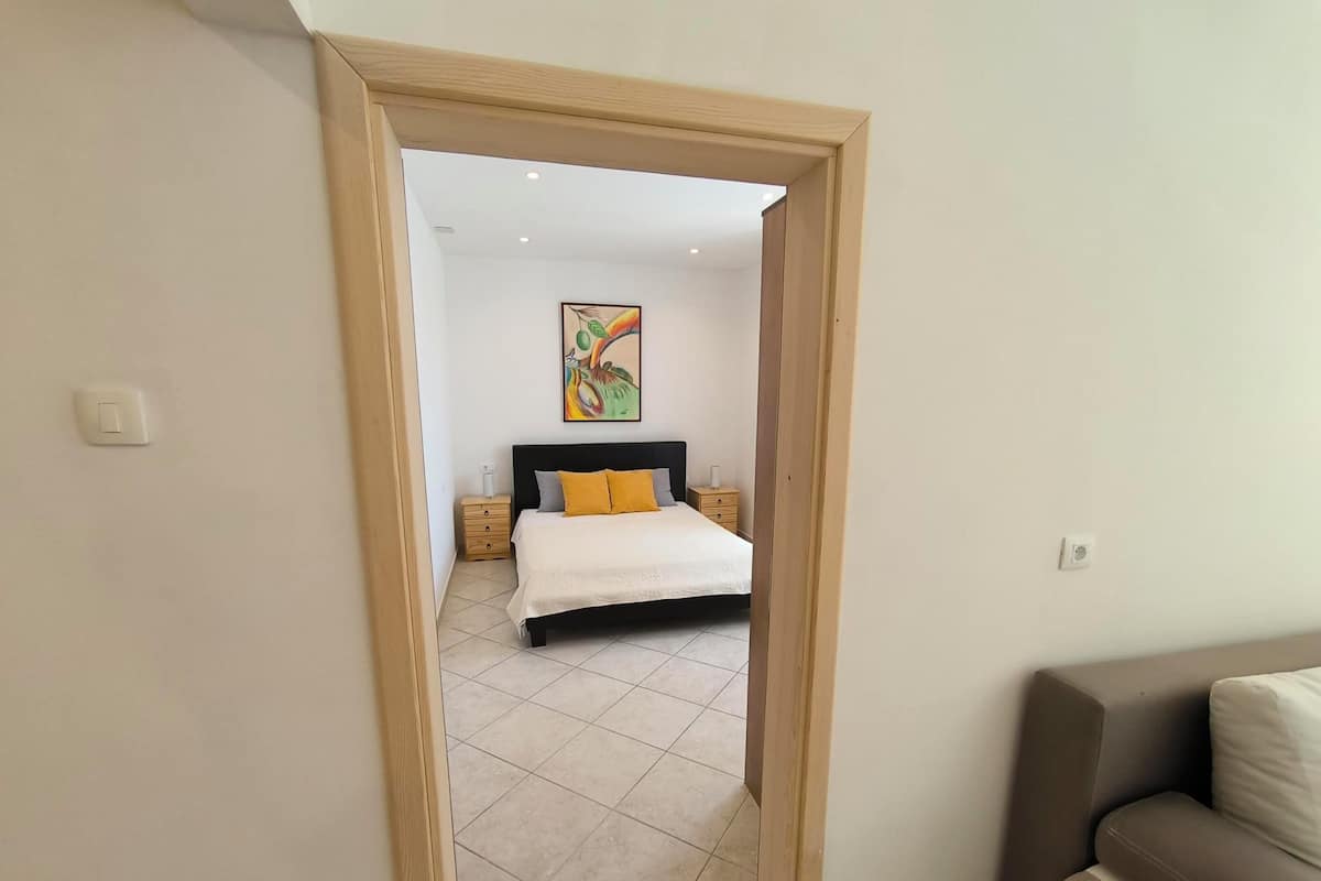 Een slaapkamer met een bed, nachtkastjes en een schilderij aan de muur.