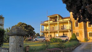 A multi-story building with balconies, a stone entrance, and a car parked in front. - Rooms and Apartment Matika (Rovinj)