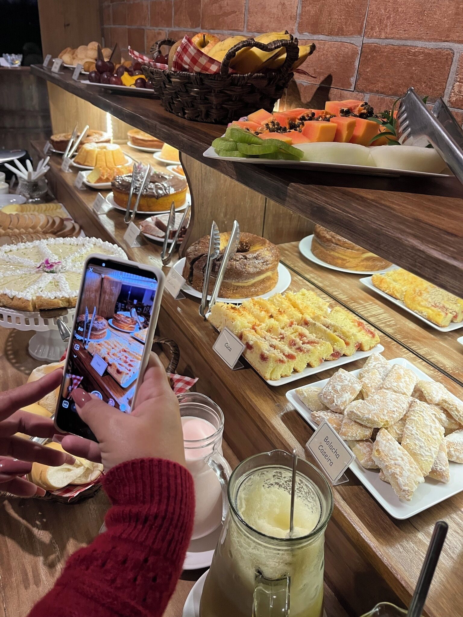 A buffet with various desserts and a person taking a photo.