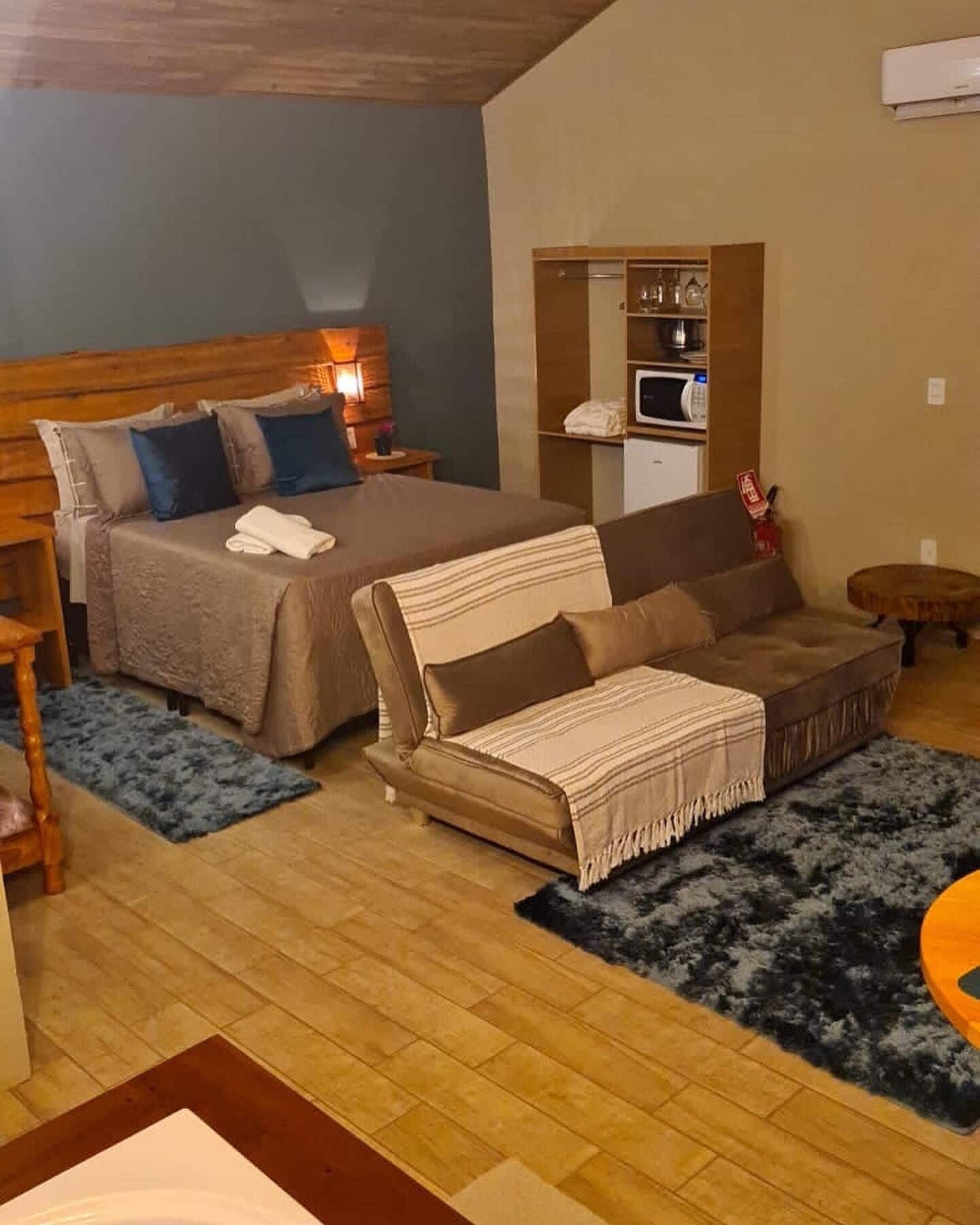 Une chambre avec un lit, un canapé, une petite table et un four à micro-ondes.