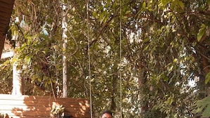 A wooden deck with a swing set, surrounded by dense foliage. - Pousada Recanto dos Canyons (Praia Grande)