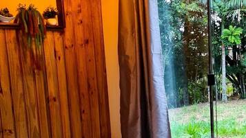 A spa room with a large white bathtub, wooden paneling, and a view of greenery outside.