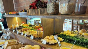 A buffet with various food items and beverages, including bread, pastries, and a selection of juices. - Pousada Recanto dos Canyons (Praia Grande)