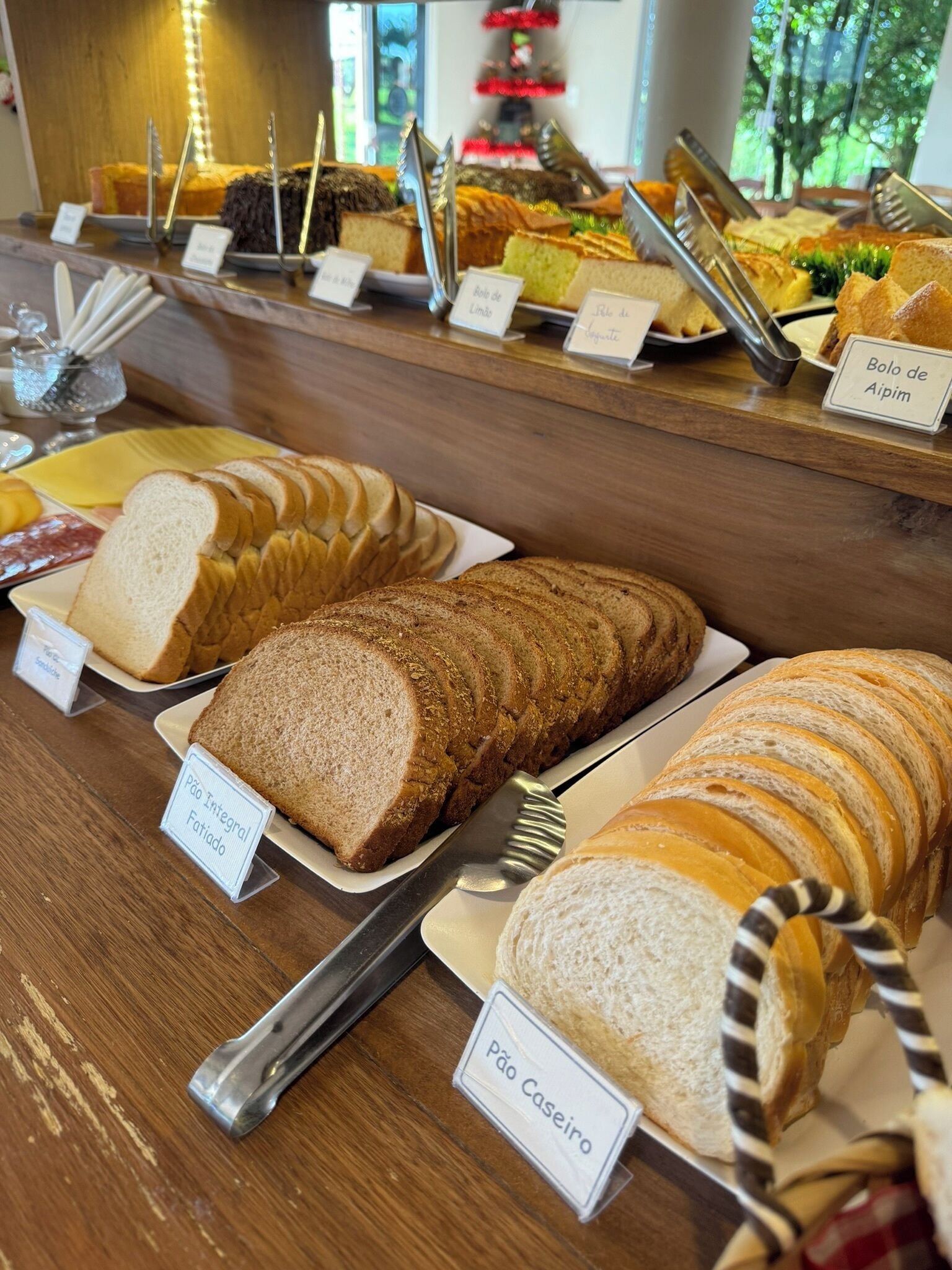 Mostrador de panadería con diferentes tipos de pan, incluyendo pan integral y blanco, con etiquetas para facilitar la elección.