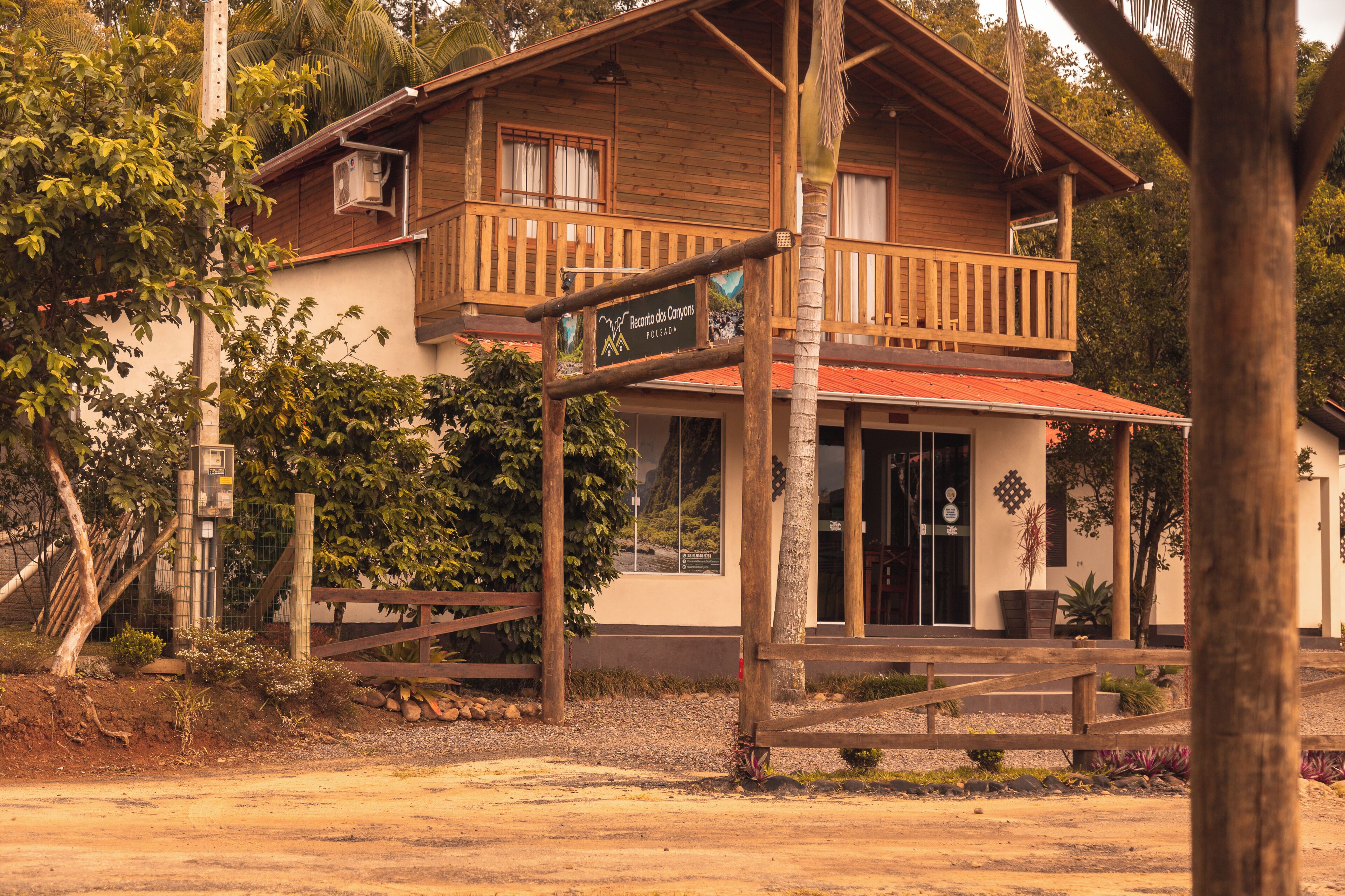 A two-story wooden building with a balcony, a signboard, and a red roof.