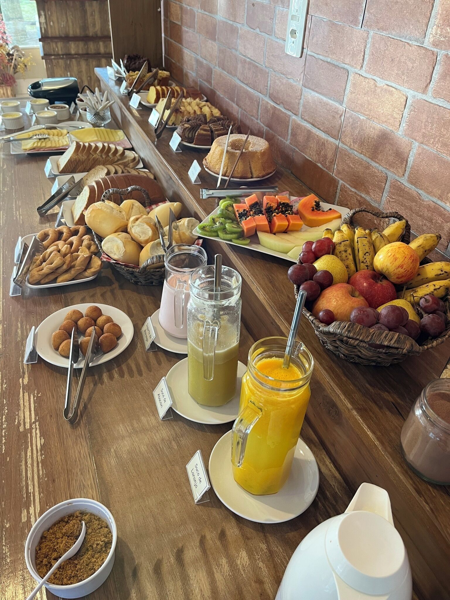 A buffet with various food items and drinks, including pastries, fruits, and a green smoothie.