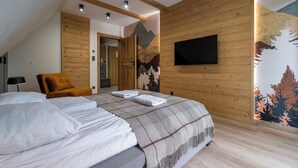 Una camera da letto con un grande letto, soffitto in legno, televisione a parete e un murale.