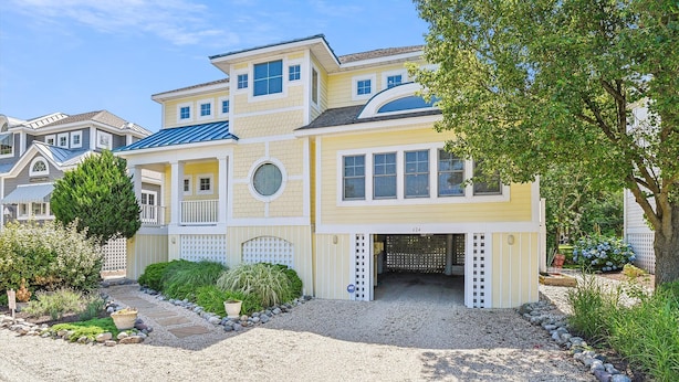 A two-story house with a front porch, a garage, and a well-maintained garden. - Spacious 4 Bedroom, Sleeps 10. Walk everywhere! (Bethany Beach)