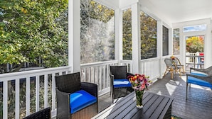 A covered porch with wicker furniture, a table, and a vase of flowers. - Spacious 4 Bedroom, Sleeps 10. Walk everywhere! (Bethany Beach)
