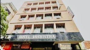 A multi-story building with a sign for 'Hotel Vashistha' at the ground level. - Hotel Vashistha (Prayagraj)