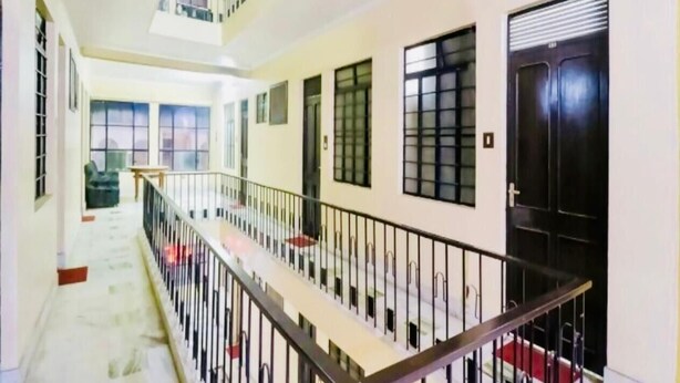 A multi-level corridor with a staircase, black-framed windows, and a black door. - Hotel Vashistha (Prayagraj)