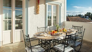 A round table set for a meal with chairs, a vase with flowers, and a view of the city.