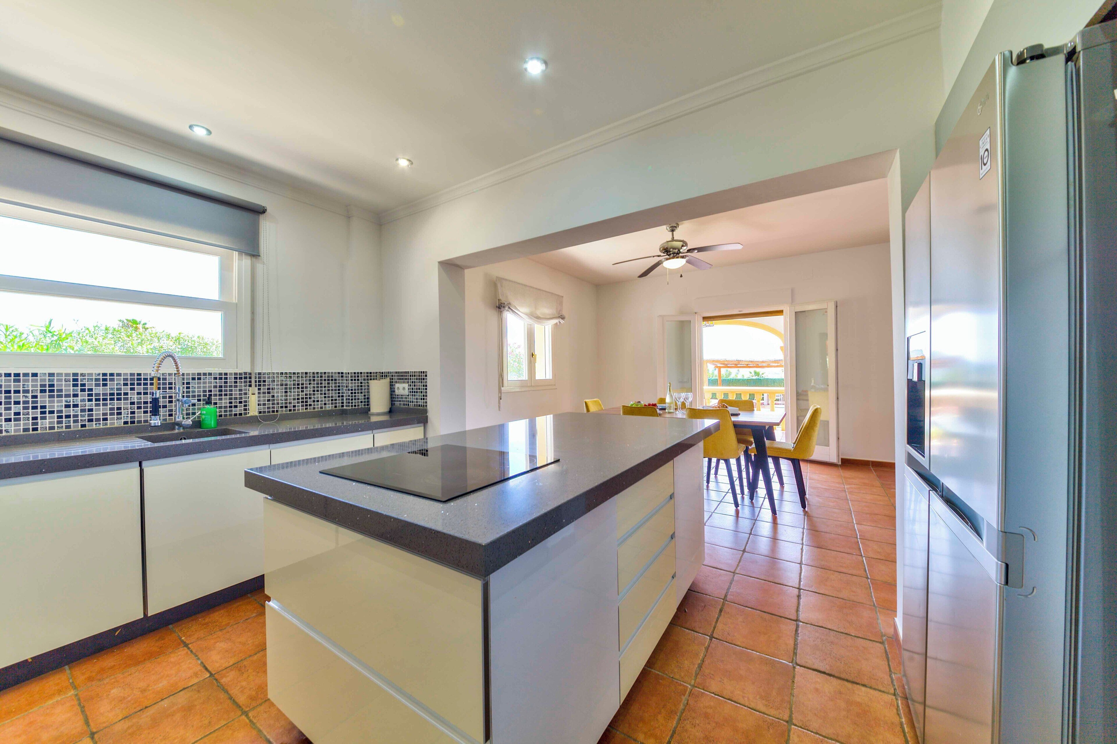 A modern kitchen with a central island, white cabinetry, and a view to the dining area.