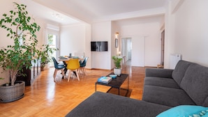A spacious living room with a grey sofa, a coffee table, and a dining area with chairs and a table. - Edem Beach Apartment by Alimos Marina (Alimos)